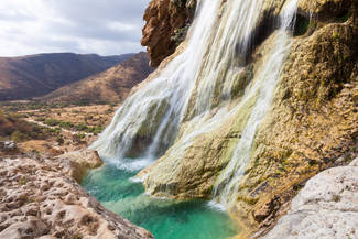 Ein großer Wasserfall schießt aus dem Wadi Darbat über die Felskante
